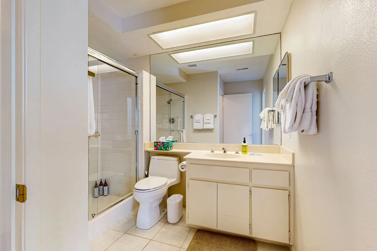 A bright bathroom with a vanity, mirror, and glass shower.