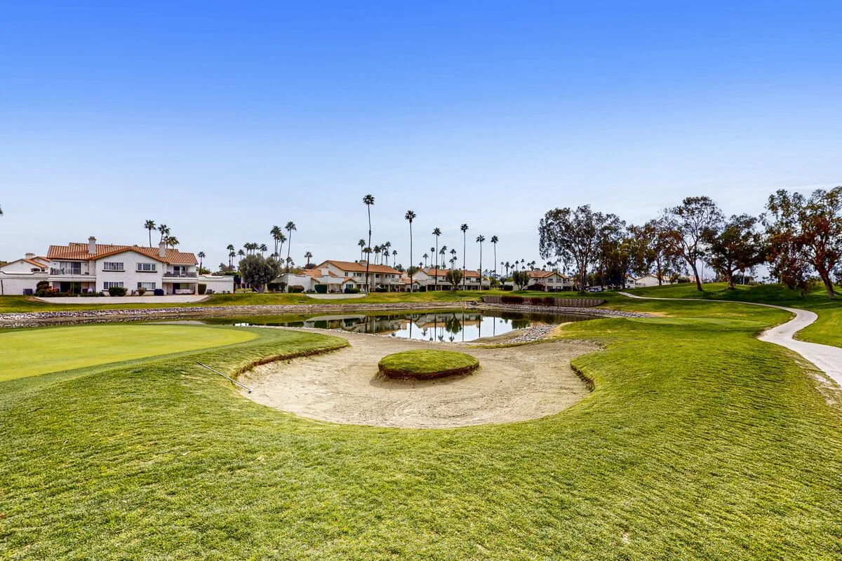 A golf course with a sand bunker, putting green, and water.