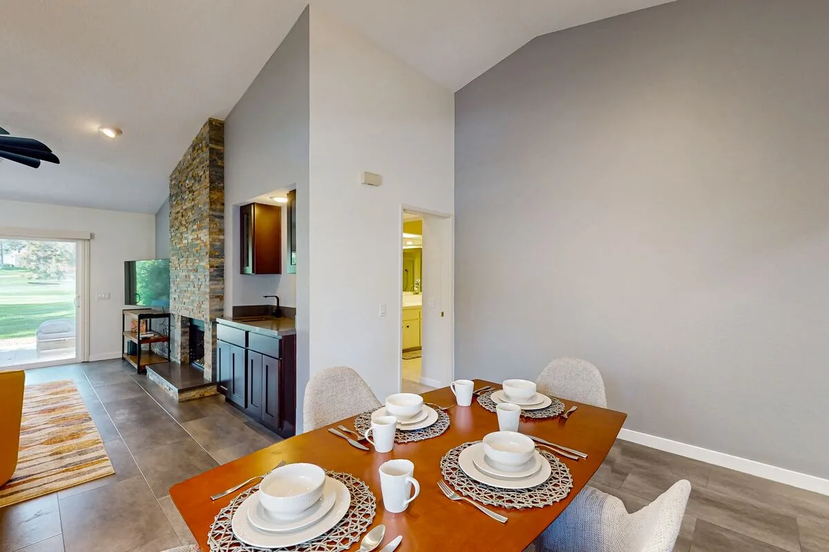 A dining area with a set table beside an open kitchen and living space.