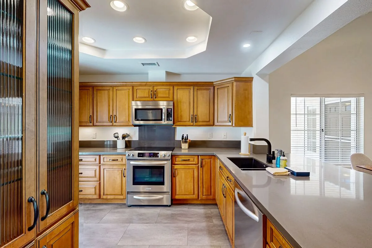 A bright kitchen with wooden cabinetry, stainless steel appliances, and a central island.