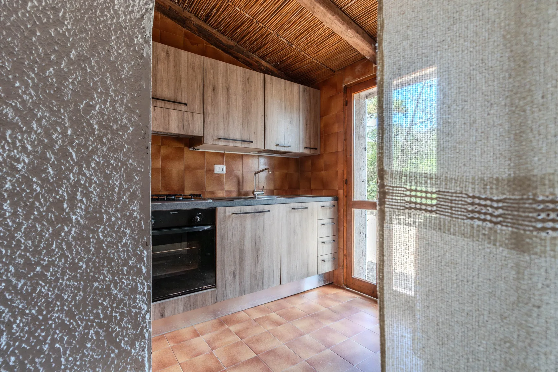 Una cocina compacta con gabinetes de madera clara y una puerta de vidrio.