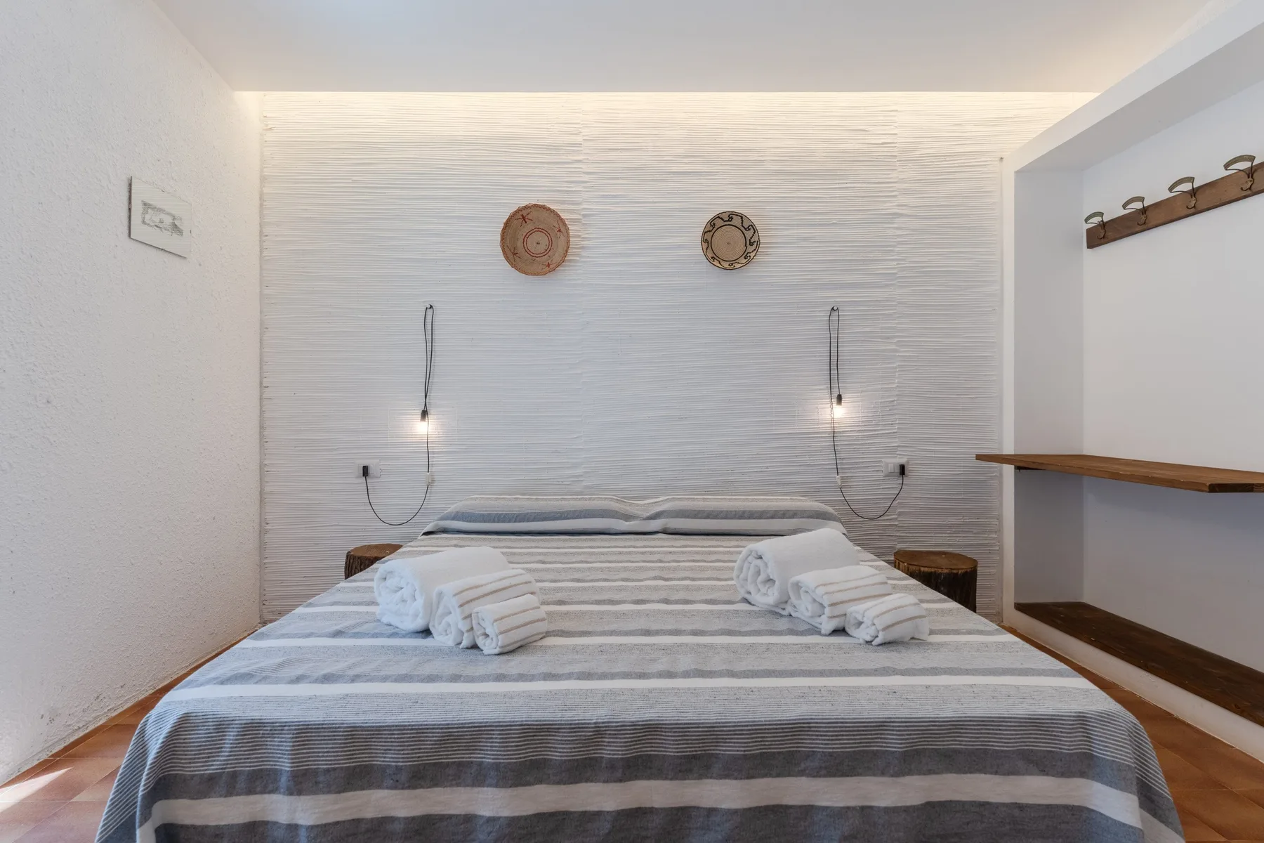 Un dormitorio con una cama a rayas y pequeñas luces de pared.