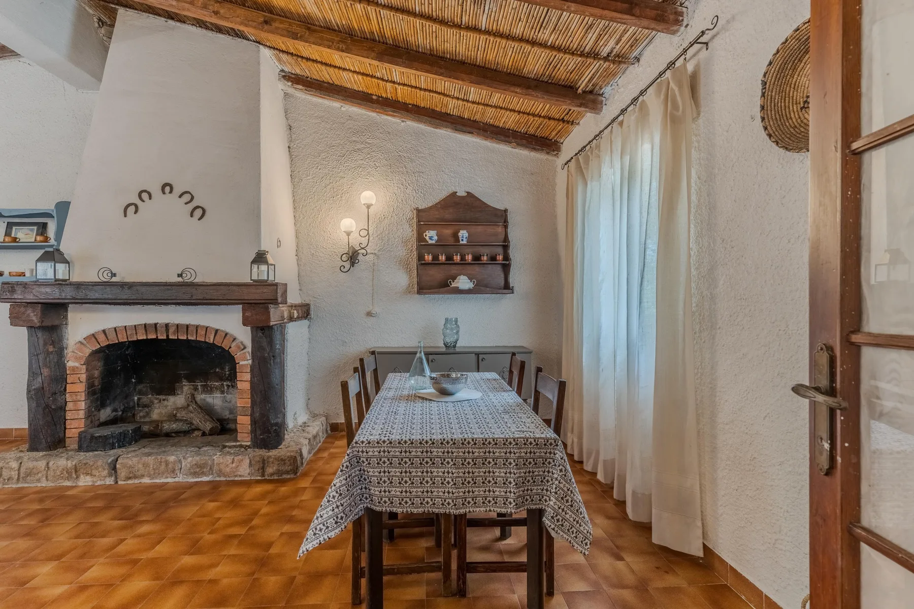 Un comedor rústico con una mesa larga bajo vigas de madera expuestas.