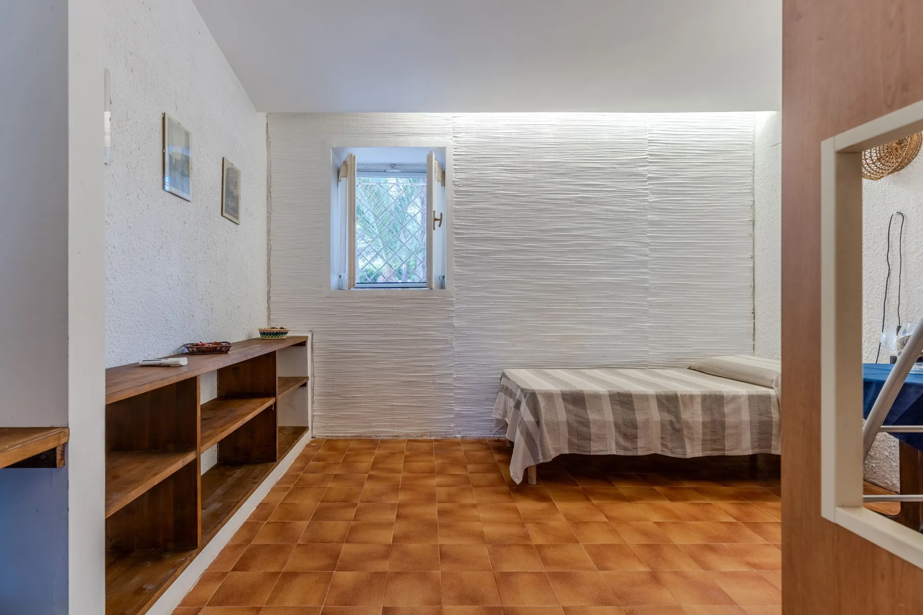 Un dormitorio con una cama, estanterías de madera y una ventana pequeña.