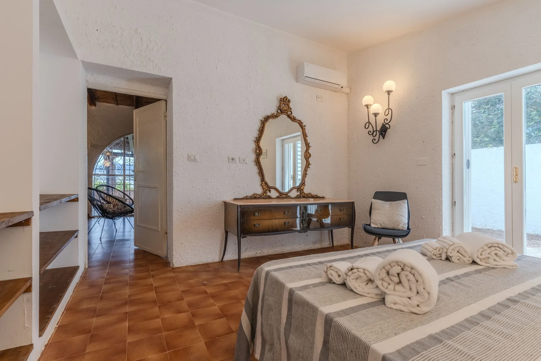Un dormitorio con una cama, una cómoda y una puerta abierta.