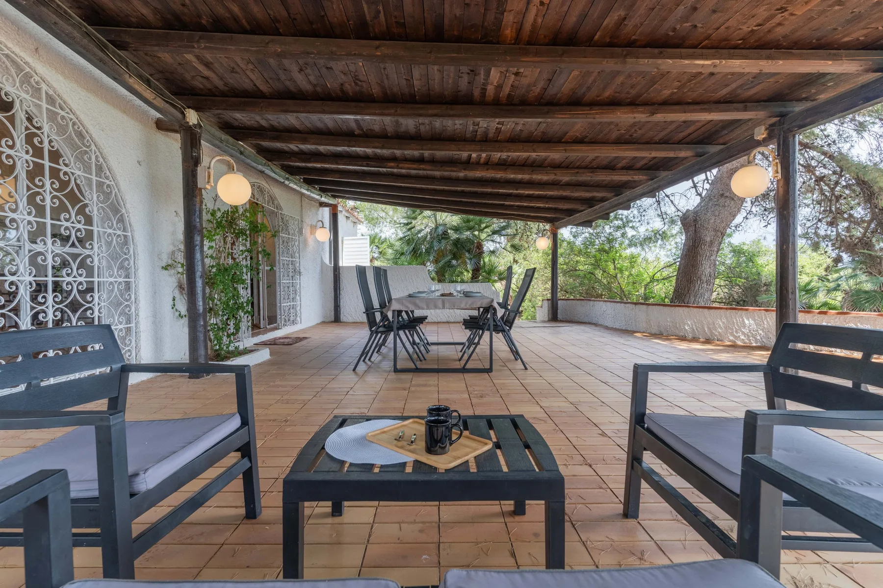 Un patio exterior cubierto con asientos y una mesa de comedor.