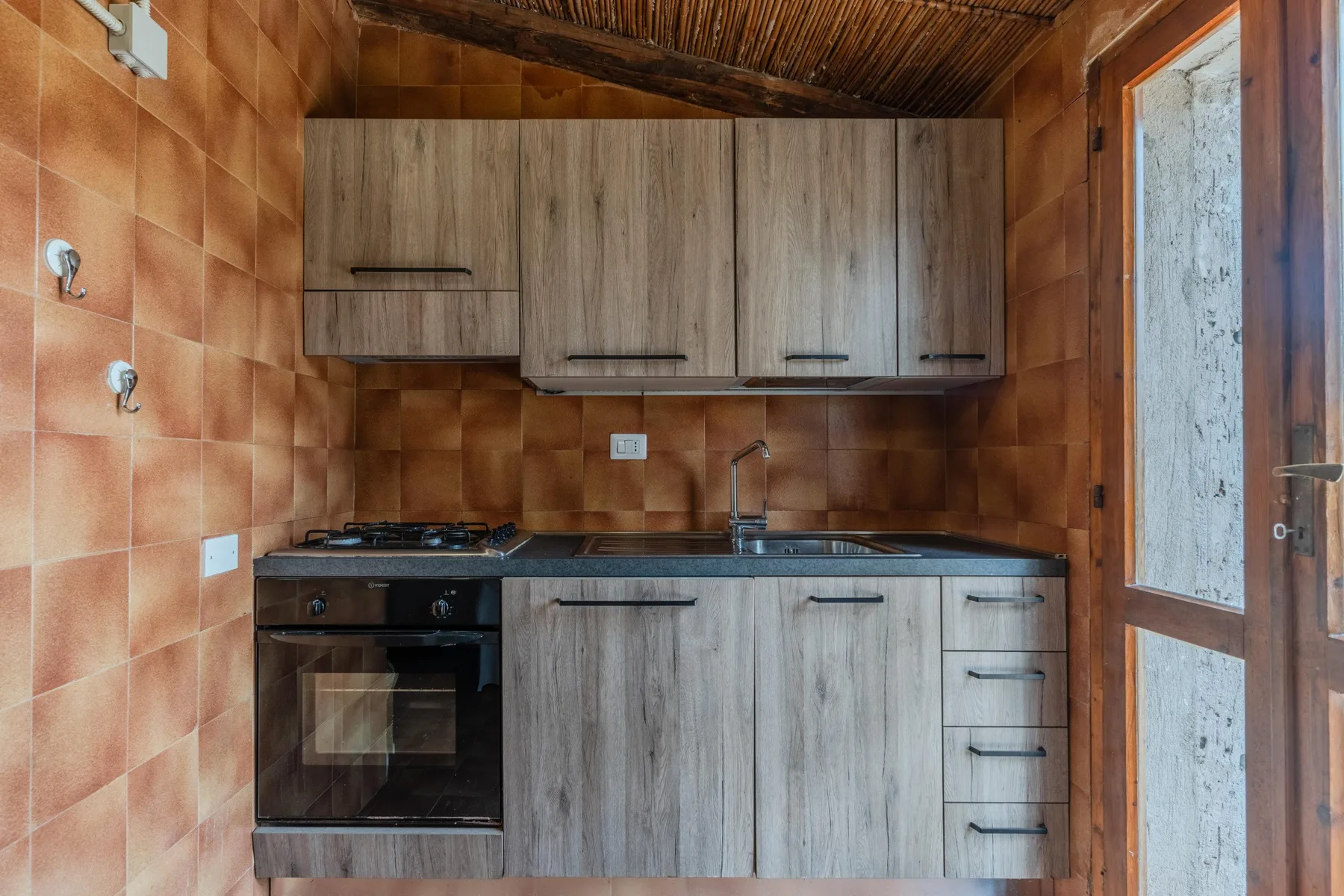 Una cocina compacta con gabinetes de acabado de madera, una estufa y un fregadero.