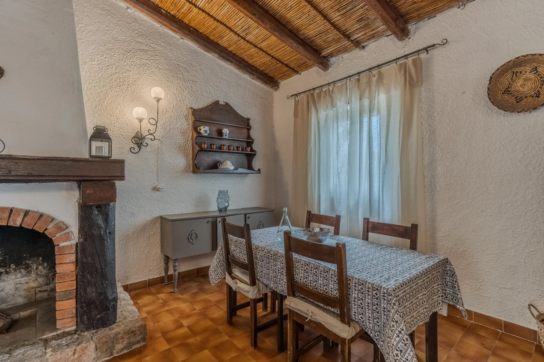Un comedor con una mesa y sillas bajo un techo de madera.