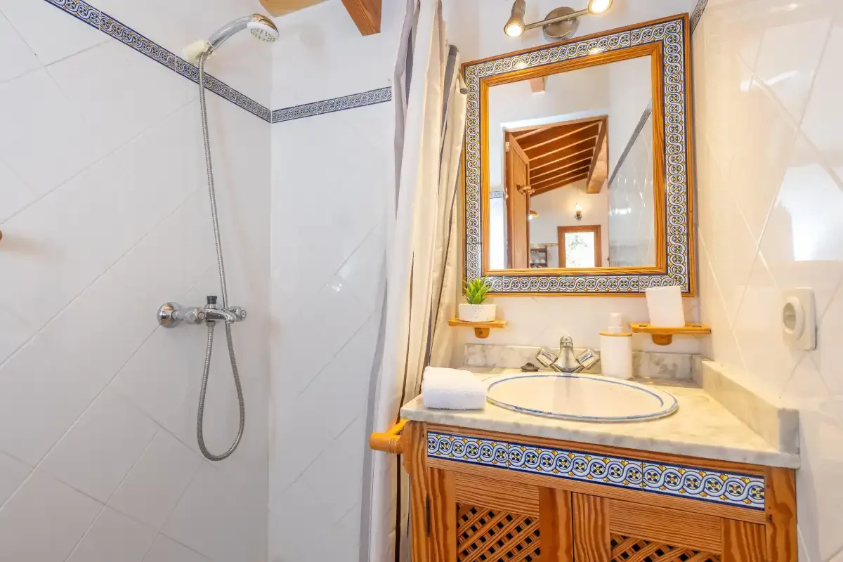 Un baño revestido de azulejos con ducha y un tocador decorado.