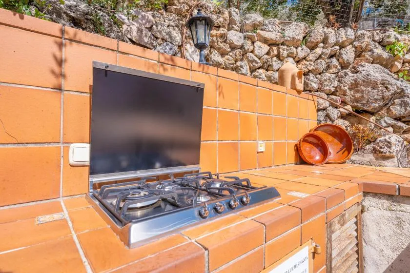 Una zona de cocina exterior con azulejos, una placa de gas y platos de terracota.