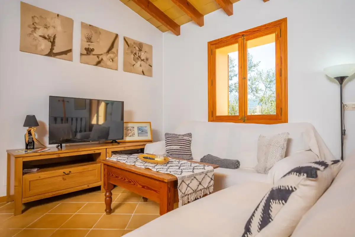 Una sala de estar con asientos, una mesa de centro de madera y un televisor.