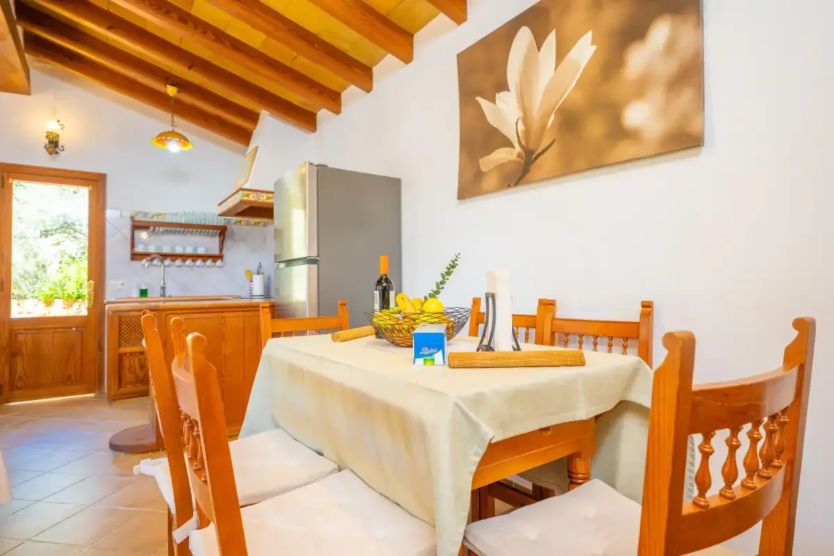Comedor con asientos de madera y una mesa junto a la cocina.