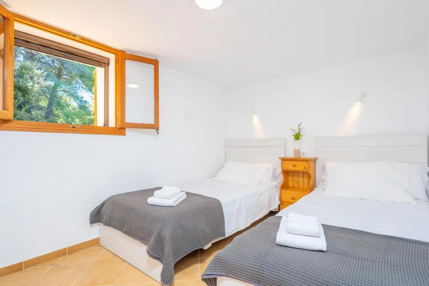 Un dormitorio luminoso con dos camas y una mesita de noche de madera.