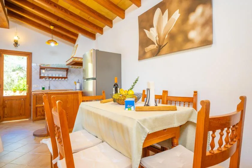 Comedor con una mesa y sillas de madera junto a una cocina pequeña.