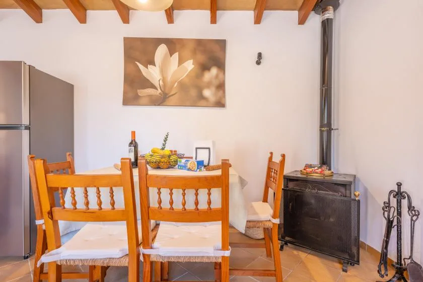 Un comedor con asientos de madera, una mesa y una estufa negra.