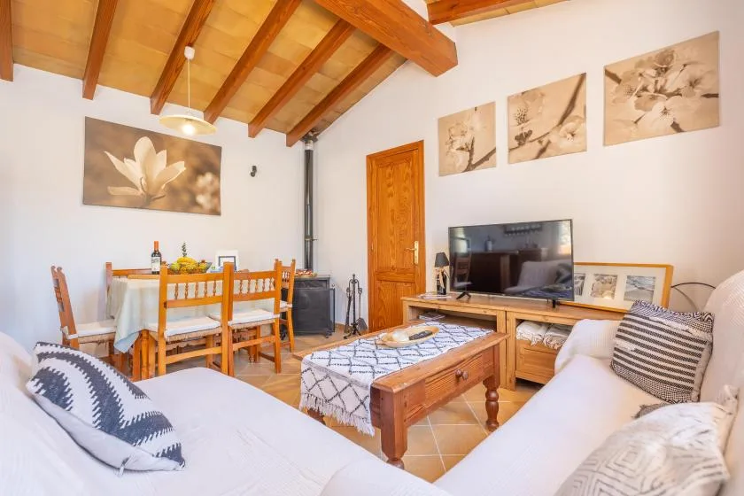 Una sala de estar con asientos, una mesa de comedor y vigas de madera a la vista.