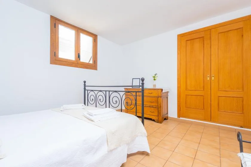 Un dormitorio luminoso con una cama, una cómoda de madera y armarios empotrados.