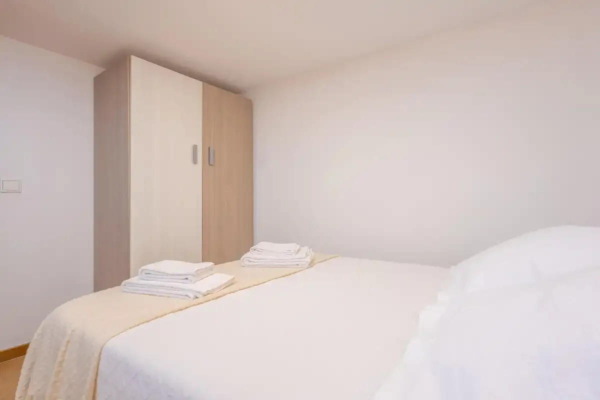 Un dormitorio con una cama bien arreglada y un armario.