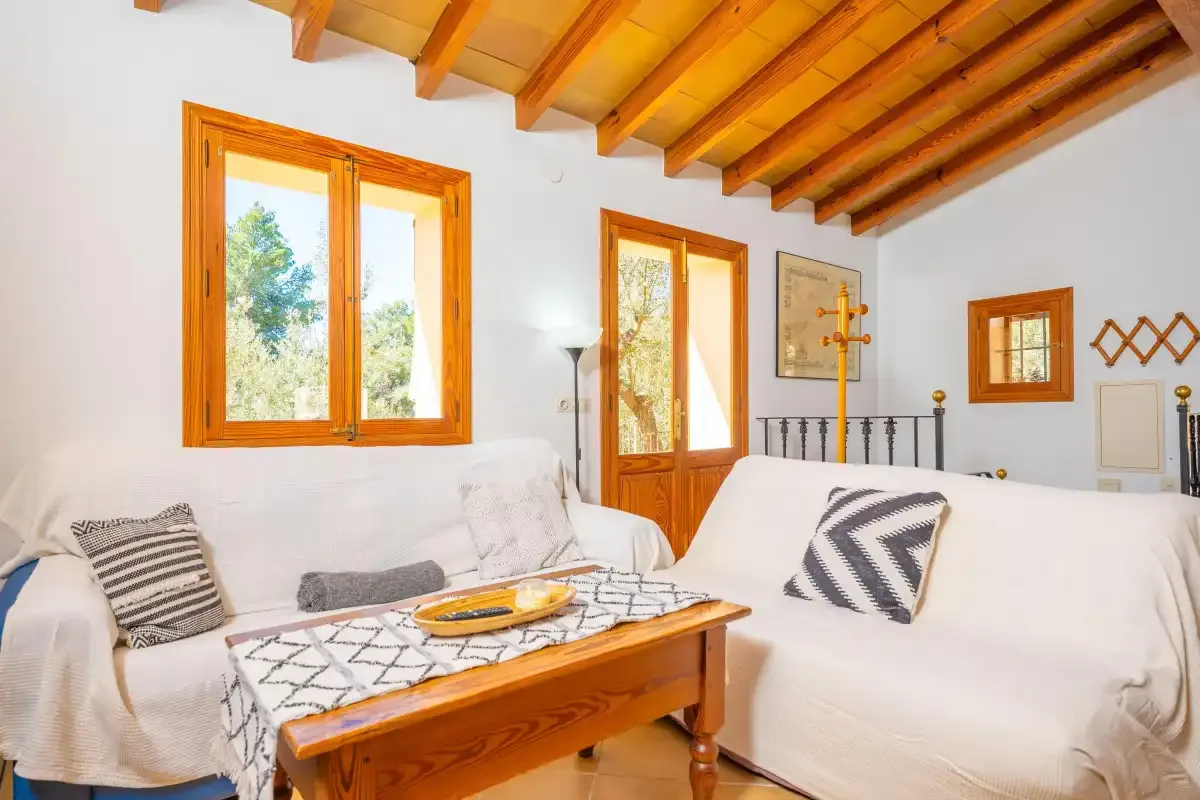 Un salón luminoso con asientos, una mesa de centro de madera y vigas vistas.