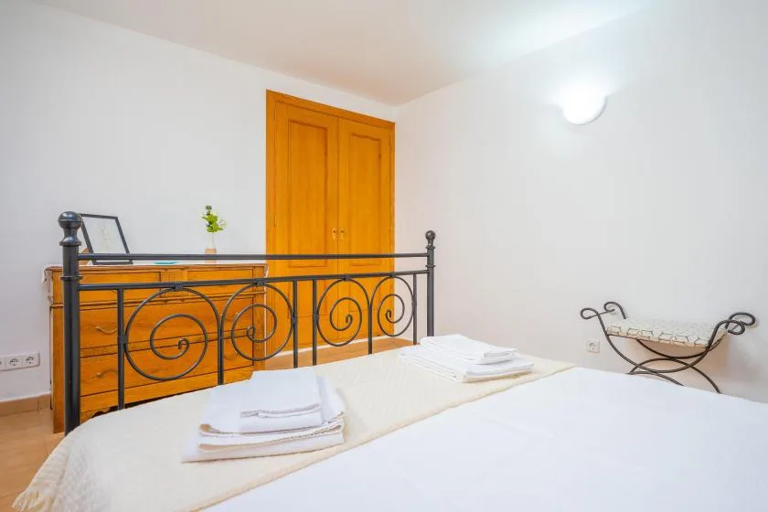 Un dormitorio con una cama, un armario de madera naranja y un marco de cama metálico oscuro.