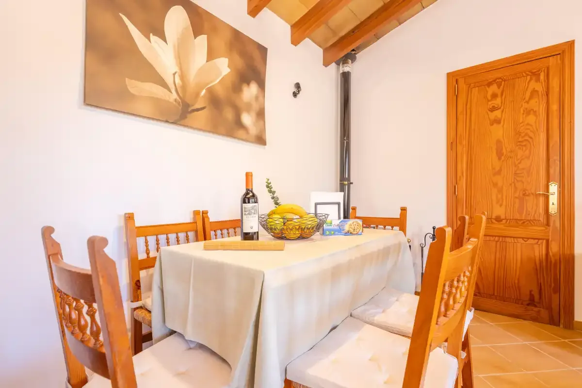 Un comedor con una mesa puesta, sillas de madera y una puerta de madera.