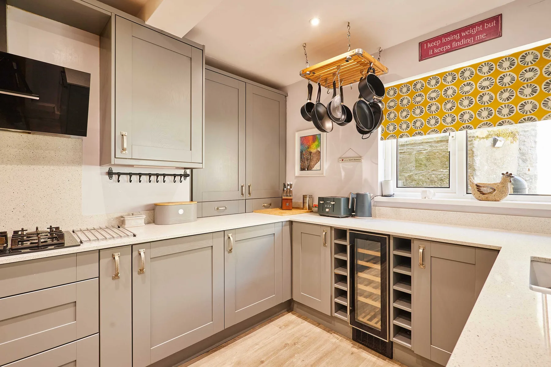 Una cocina con gabinetes grises, una placa de cocción y utensilios colgados.