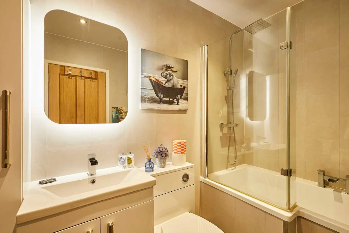 Un baño con lavabo, espejo y bañera con una mampara de ducha de vidrio.