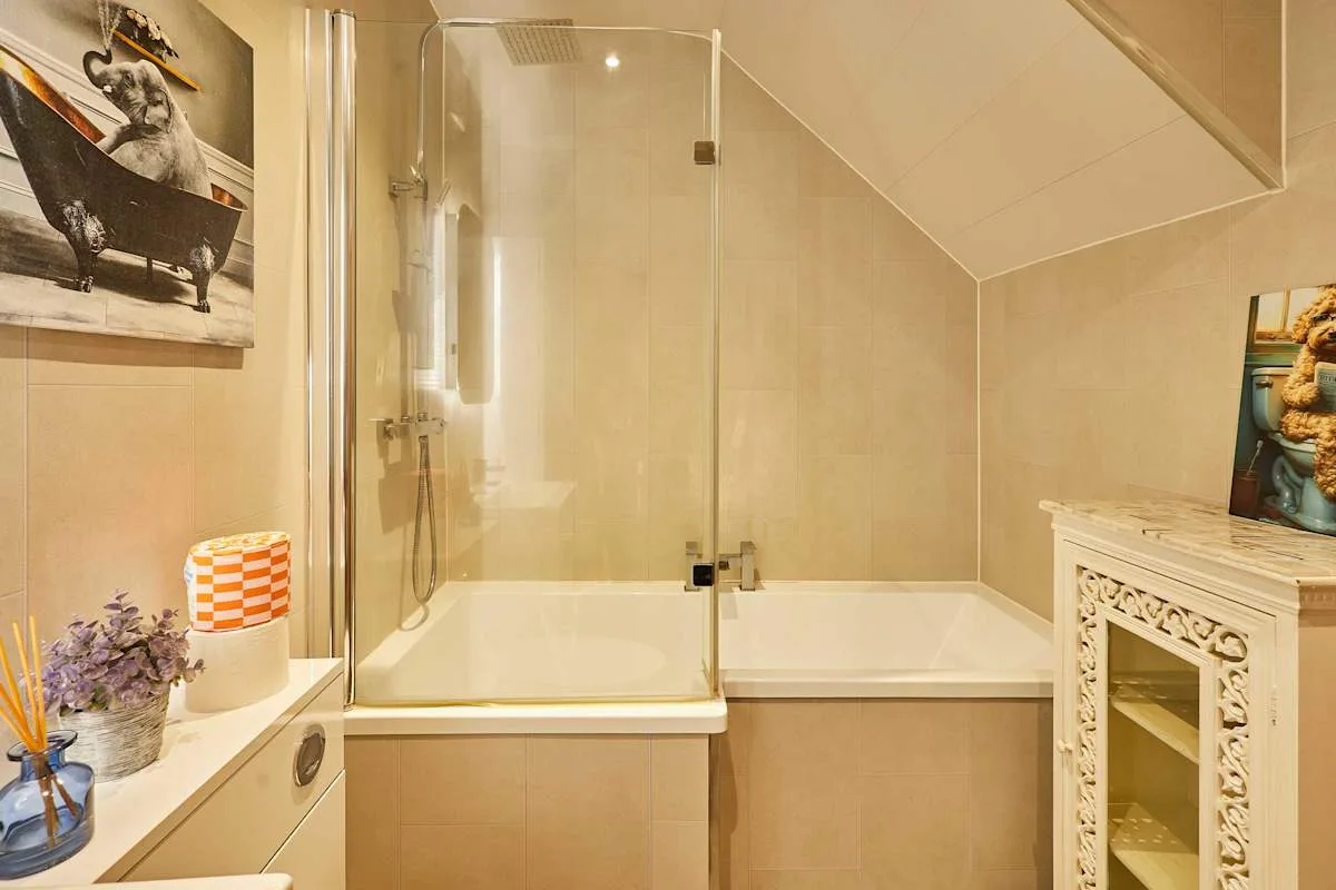 Baño con bañera, mampara de vidrio y techo inclinado.