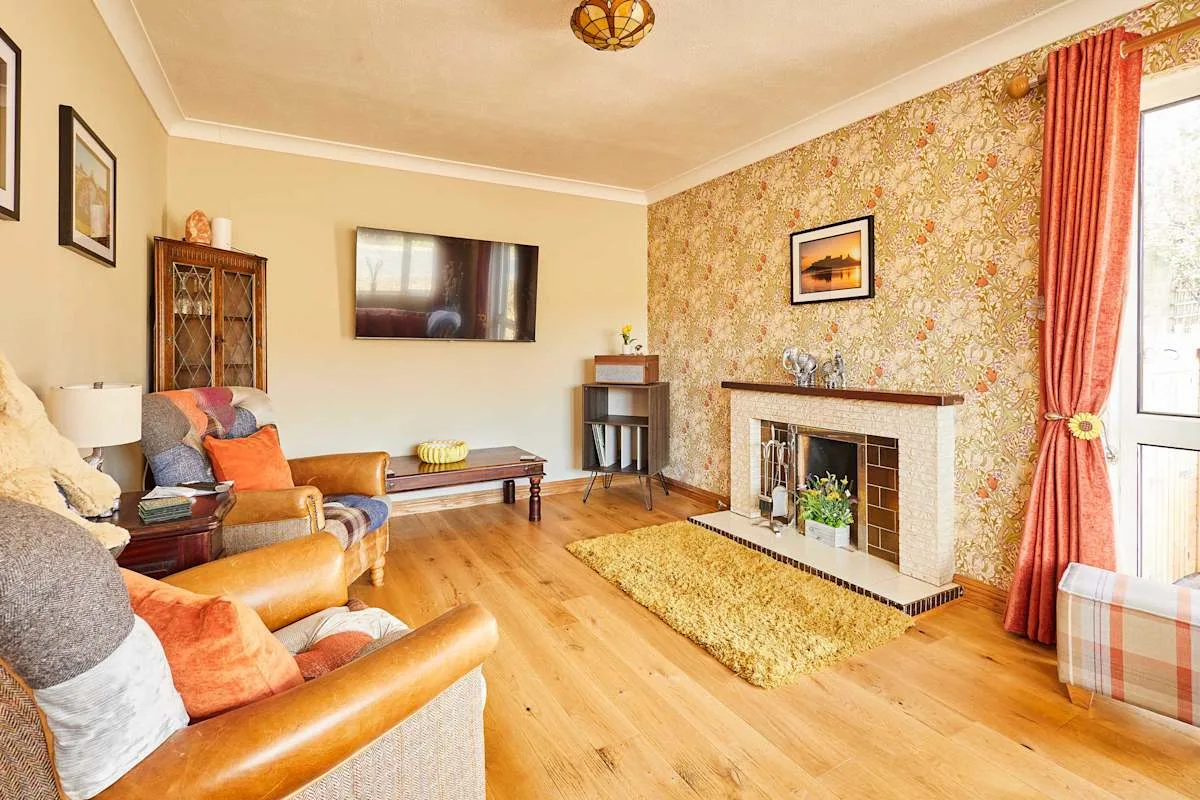 Una sala de estar con asientos frente a una chimenea y un televisor.