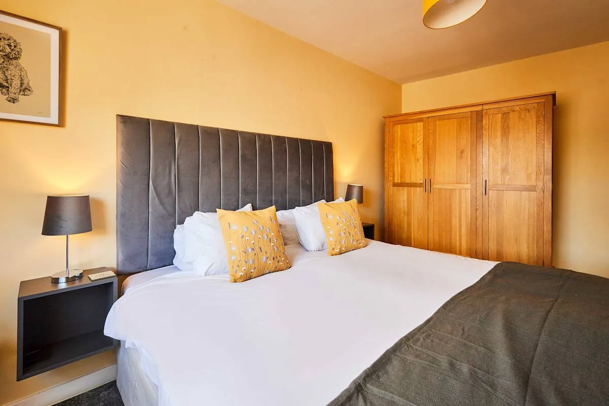 Un dormitorio con una cama grande, lámparas de noche y un armario de madera.