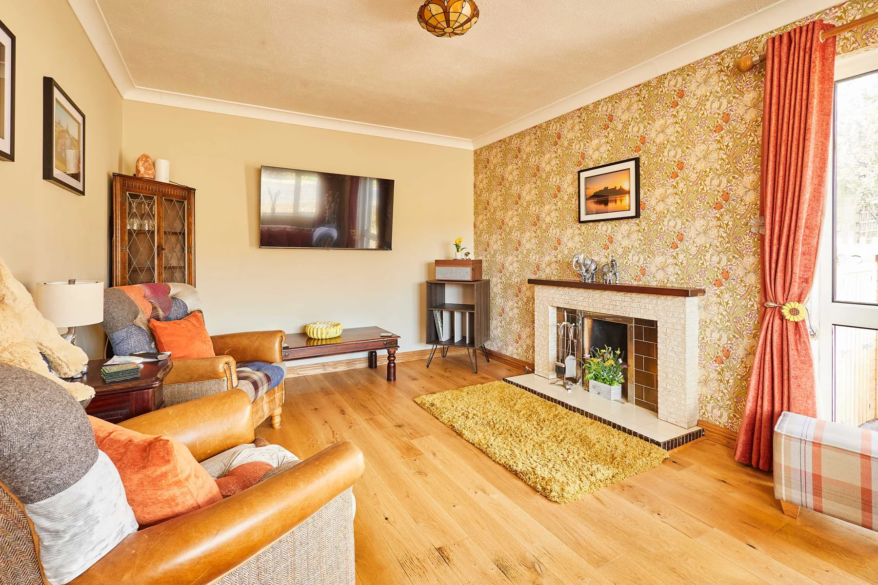 Una sala de estar con asientos alrededor de una chimenea y un televisor montado en la pared.