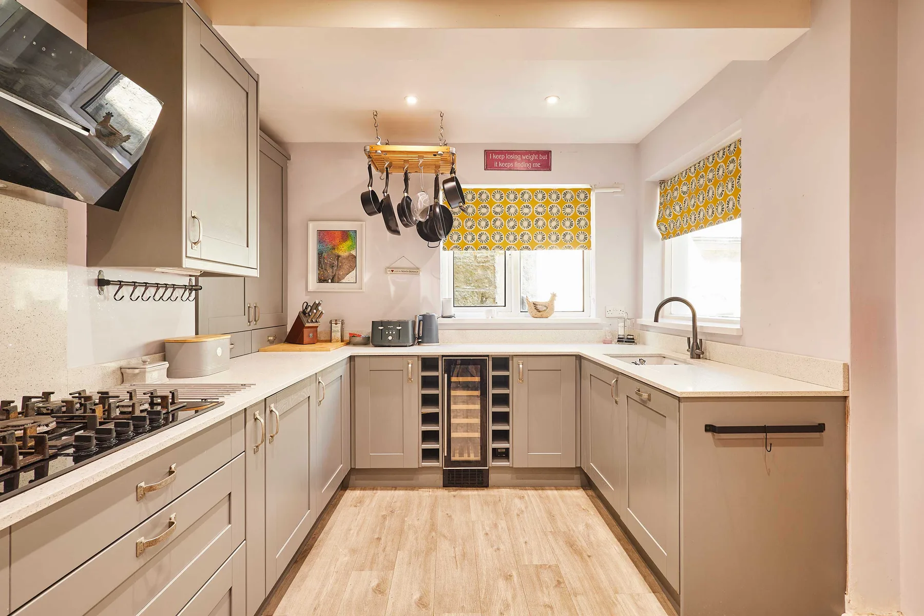 Una cocina luminosa en forma de U, con gabinetes claros, una estufa y un fregadero.