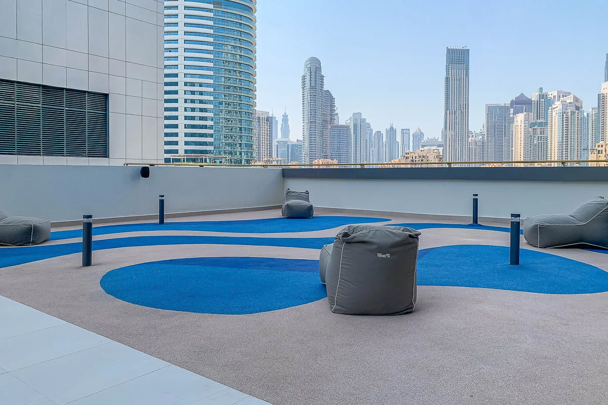 A rooftop lounge with blue seating areas and a city skyline in the background.