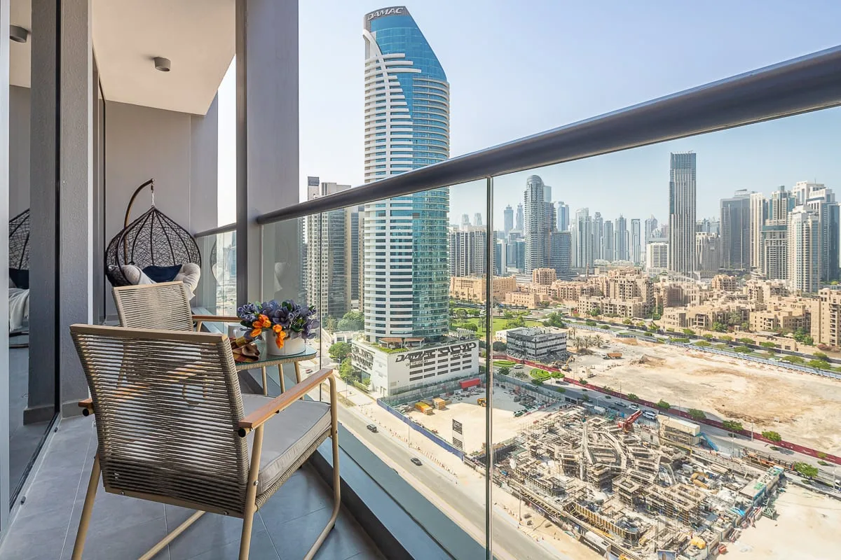 A balcony with seating overlooks a city skyline and construction site.