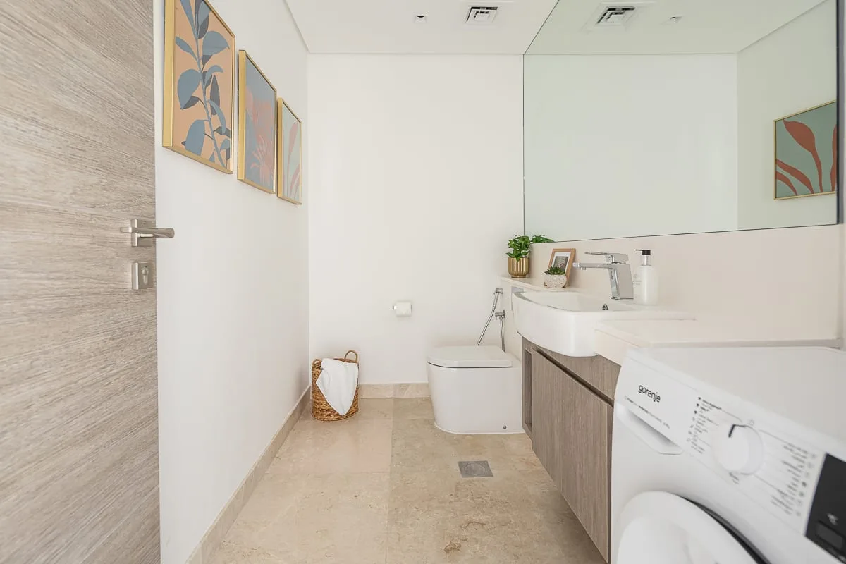 A bright bathroom with a toilet, sink, and washing machine.