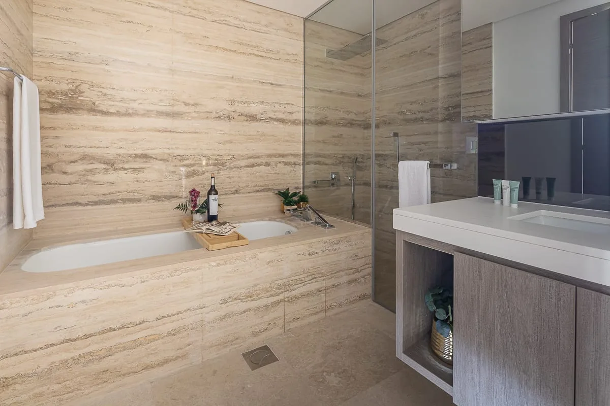 A bathroom with a bathtub, glass shower, and vanity.