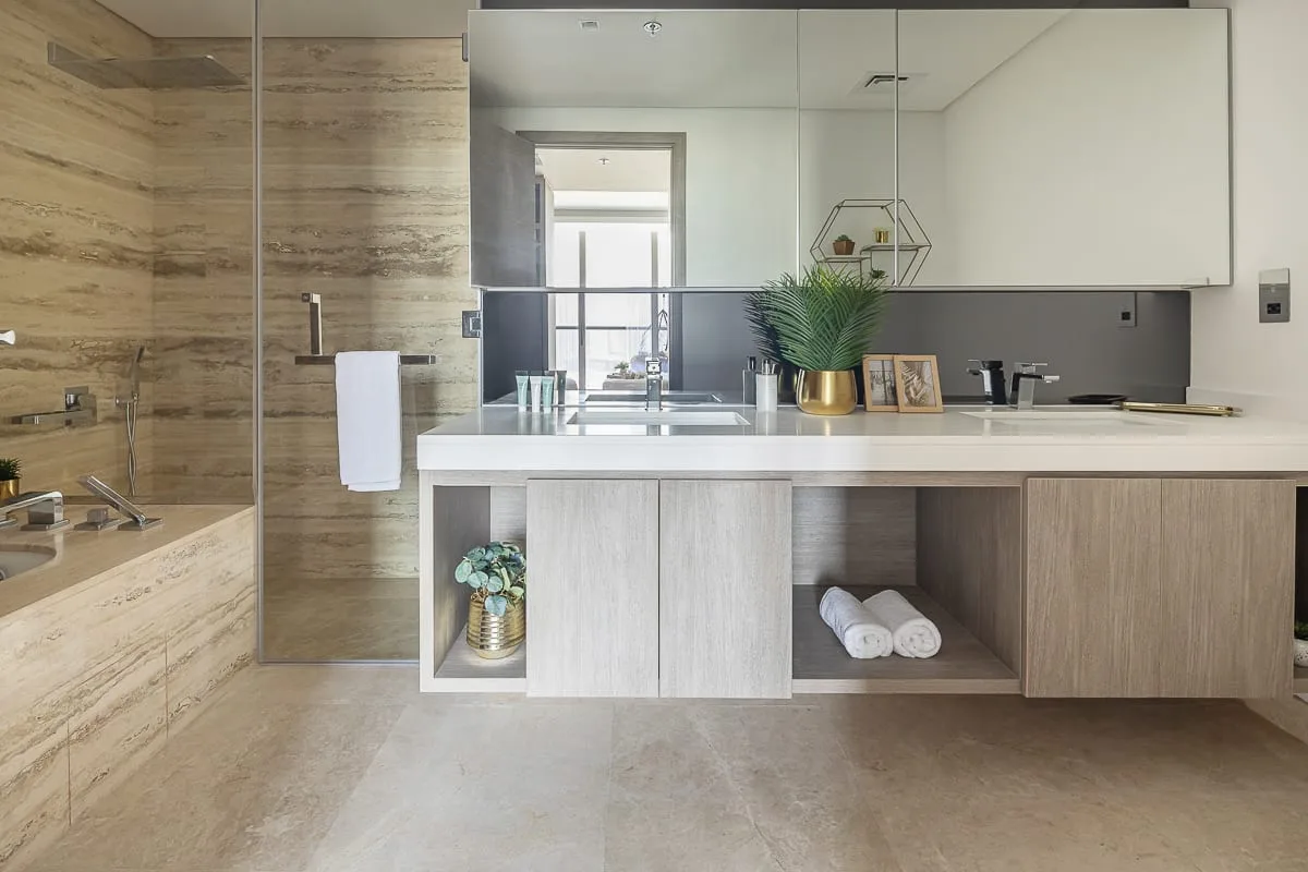 A bright bathroom has a wide vanity and a glass-enclosed shower.