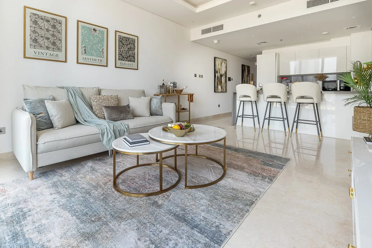 Una sala luminosa con asientos, mesas de centro y una cocina abierta.