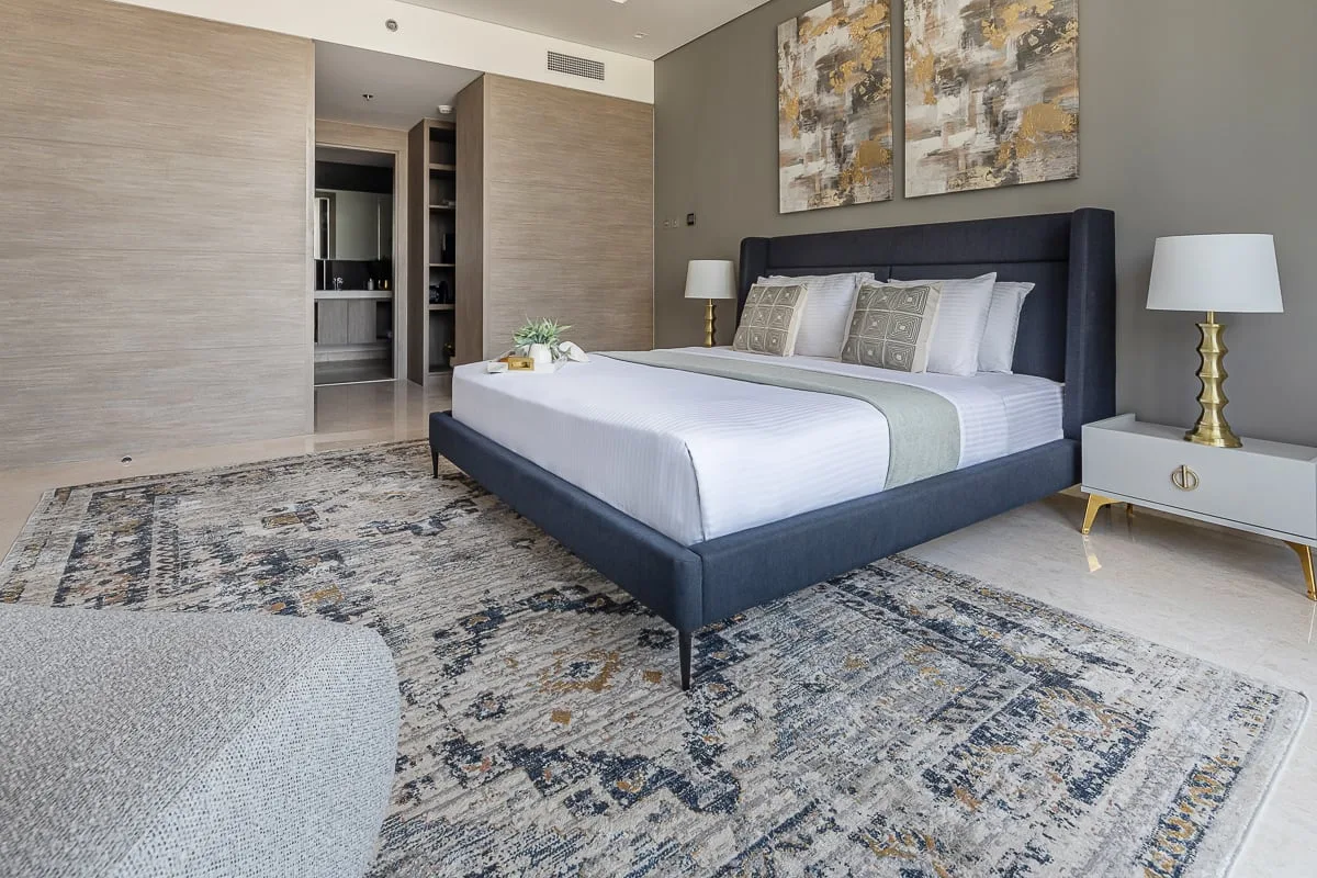 A bedroom with a large bed, matching bedside lamps, and abstract wall art.