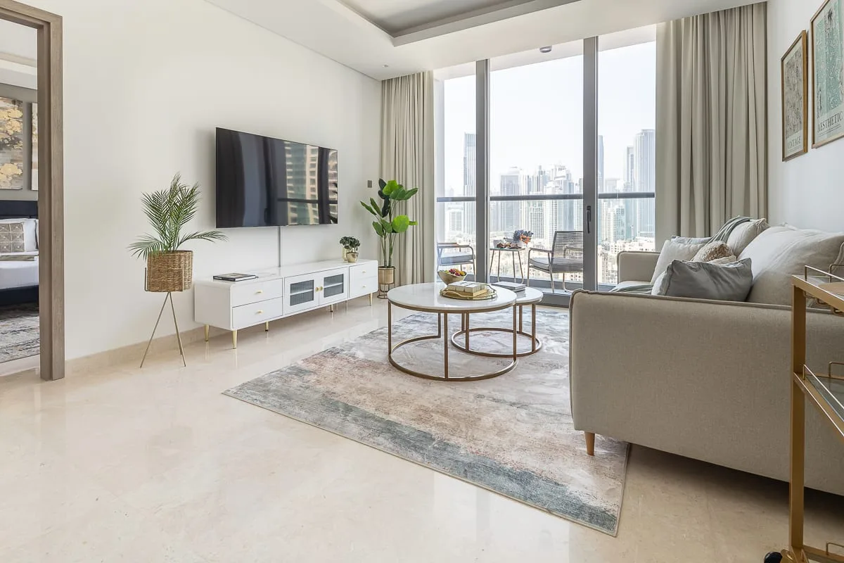 A bright living room with seating, a coffee table, and floor-to-ceiling windows.