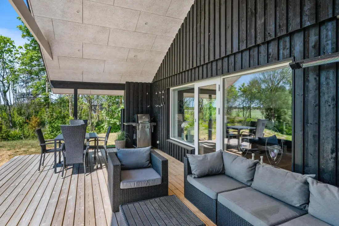 Una zona exterior cubierta con una mesa de comedor y sillas junto a la casa.