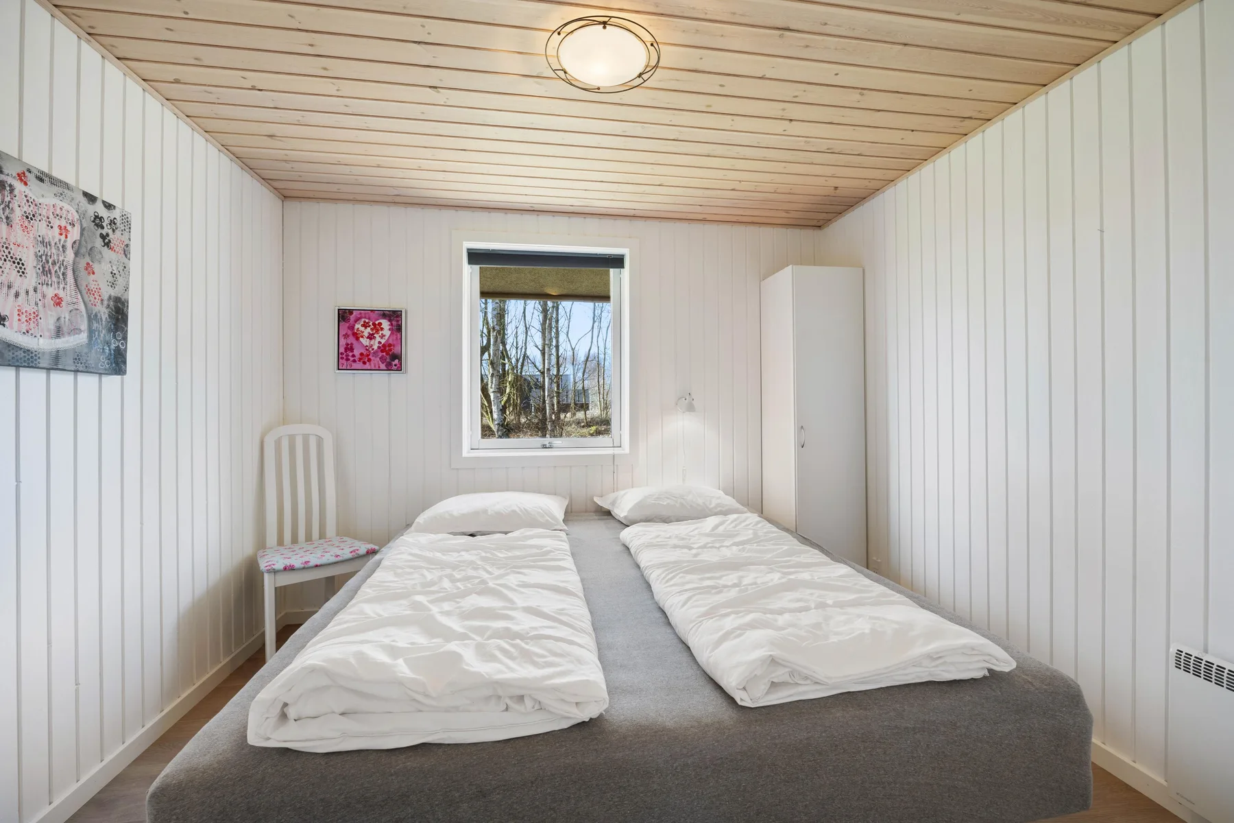 Un dormitorio con dos camas y una ventana con vistas a los árboles.
