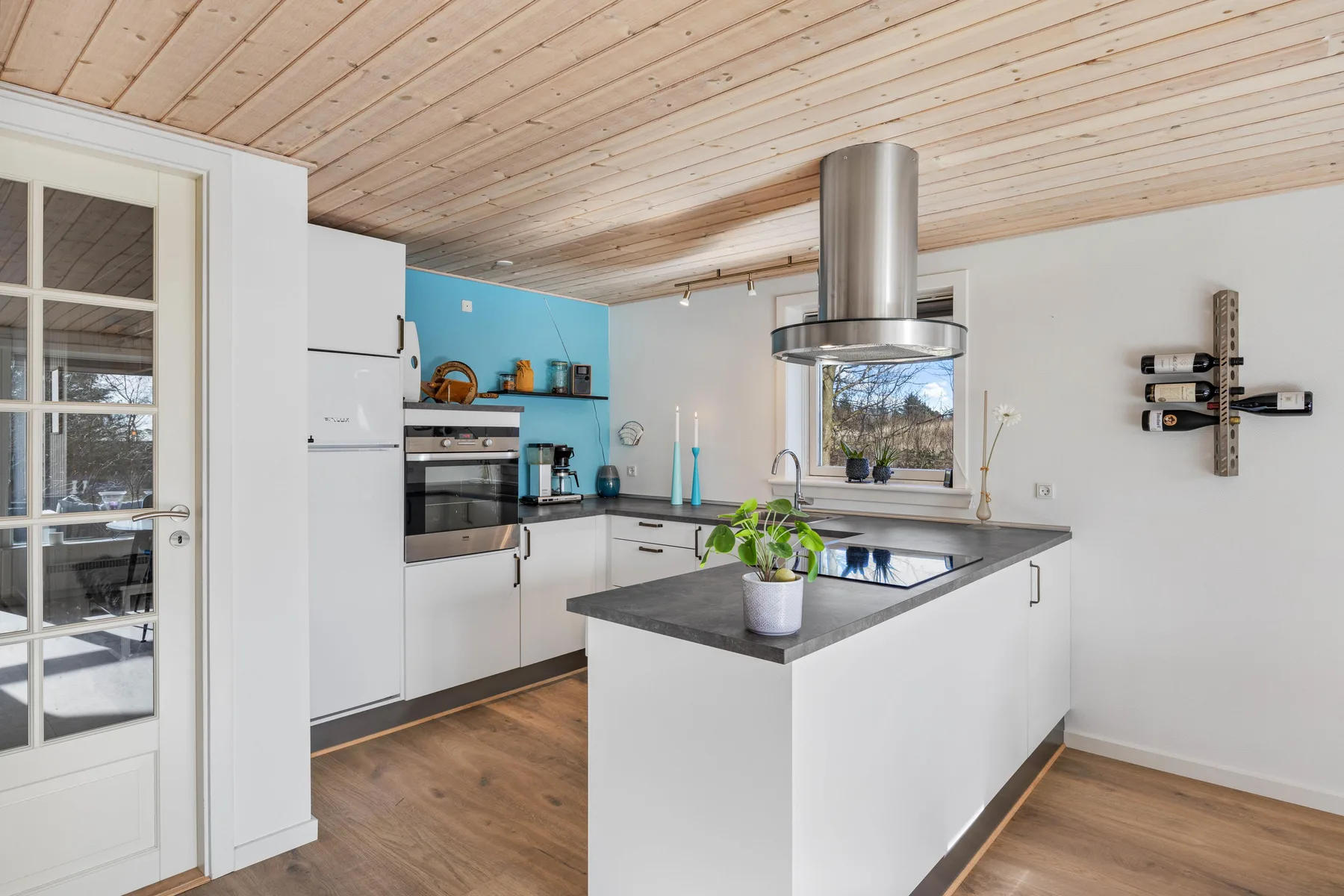 Una cocina luminosa con armarios blancos, encimeras oscuras y una isla central.