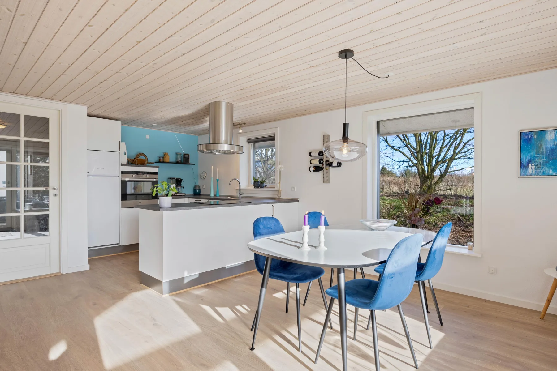 Cocina y comedor de concepto abierto con una mesa y asientos azules.
