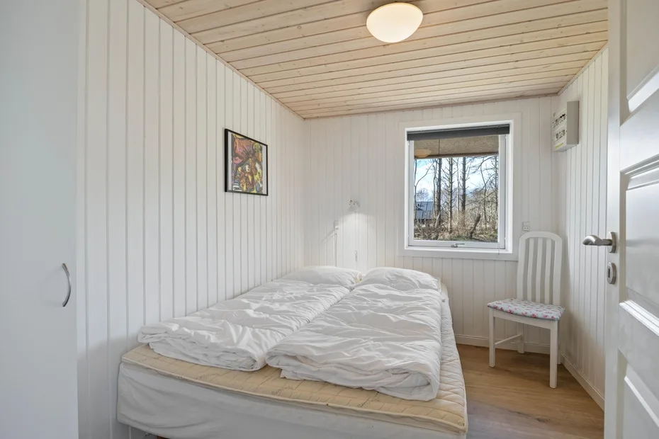 Un dormitorio con una cama, una ventana y una silla.