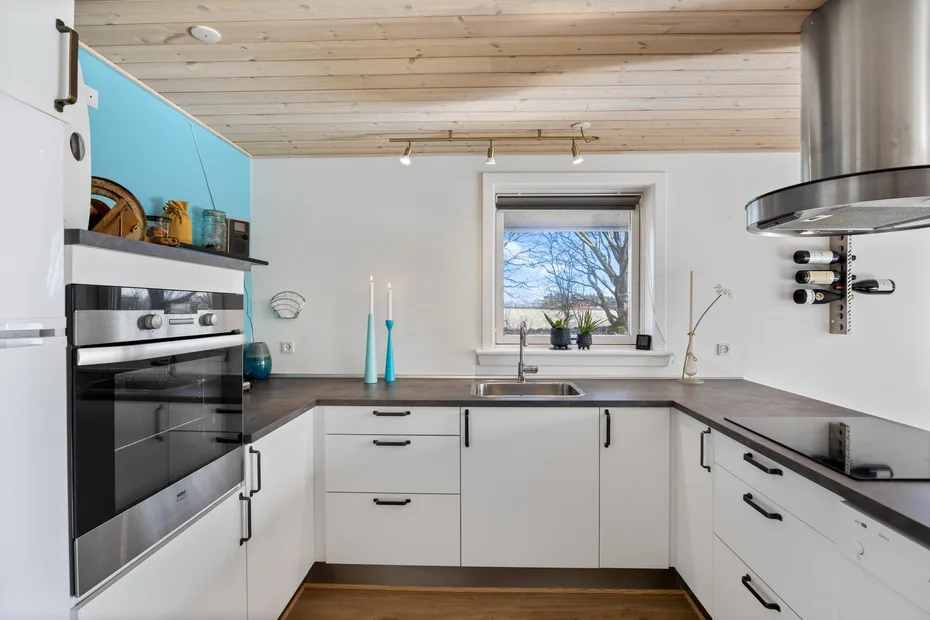 Una cocina moderna con gabinetes blancos, encimeras oscuras y una ventana.