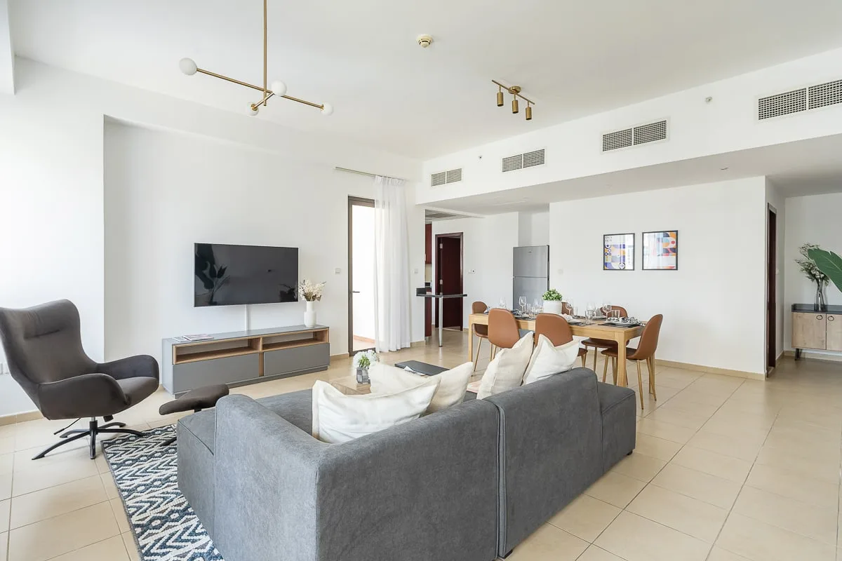 A bright open-plan living and dining area with a sofa, television, and dining table.