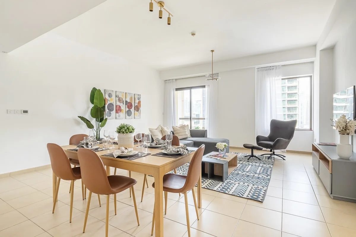 Un luminoso comedor y sala de estar con la mesa puesta y asientos junto a las ventanas.