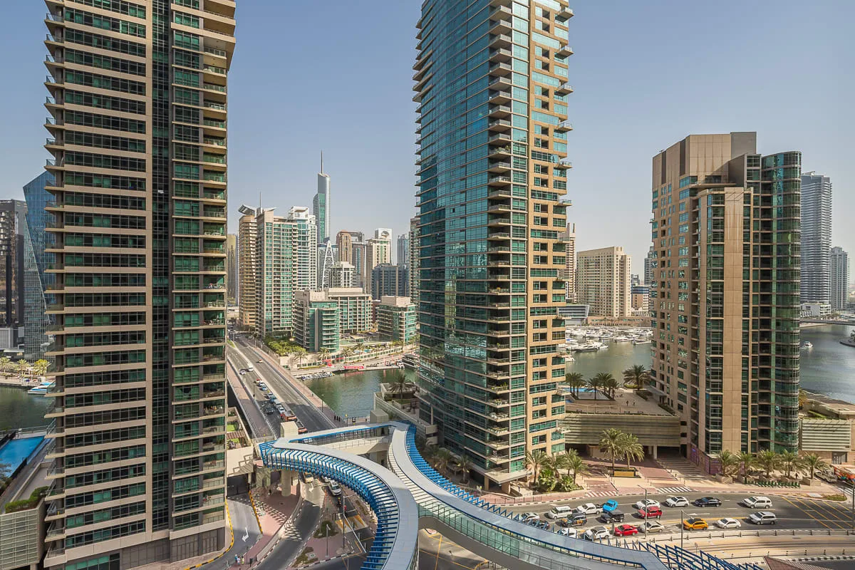 A city skyline of high-rise buildings beside a waterfront and curving elevated roadway.