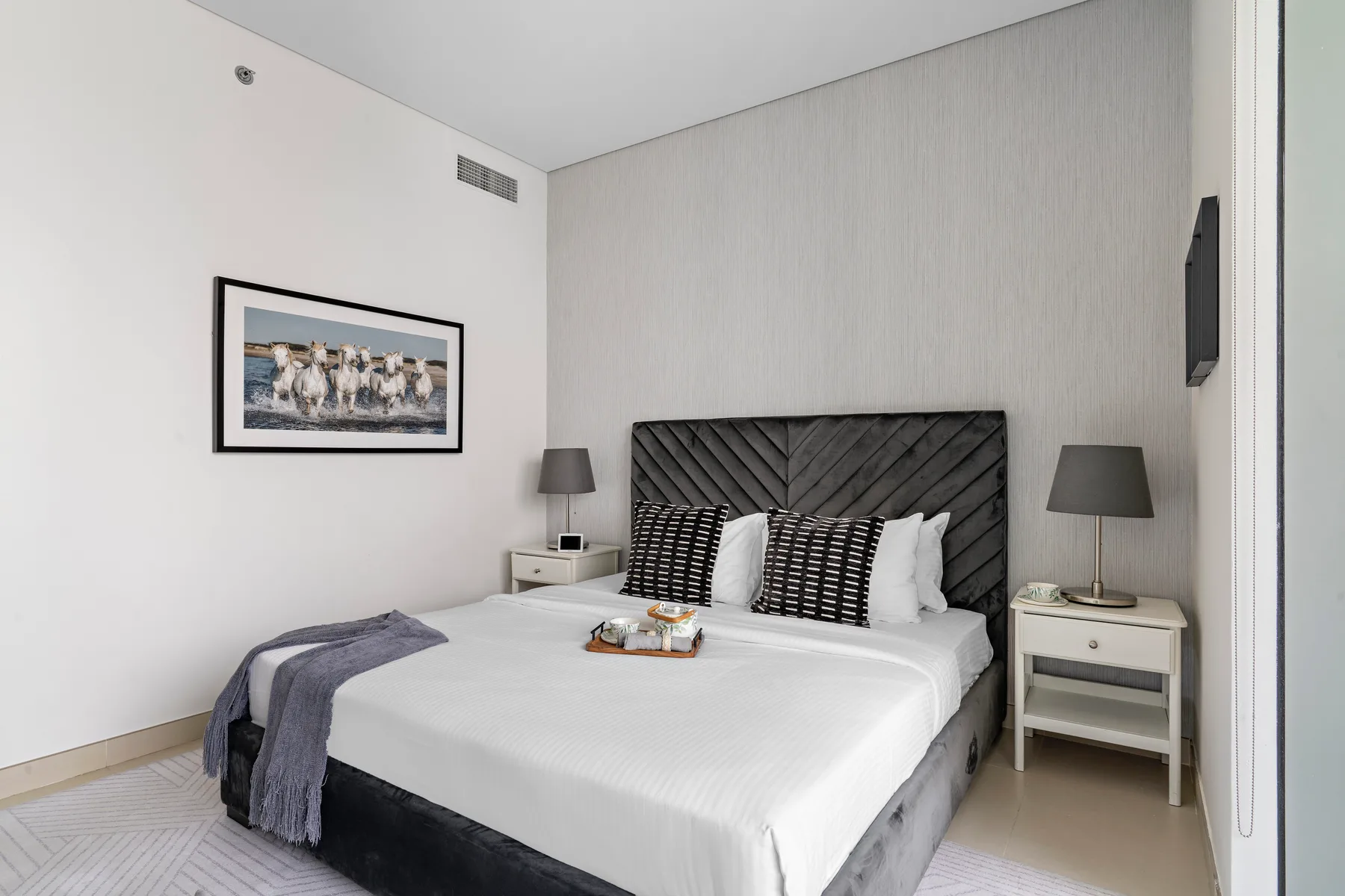 Un dormitorio con una cama grande, almohadas estampadas y mesitas de noche a juego.